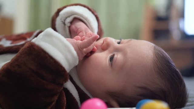 Cute baby boy playing toy. Cute child playing with rattle on bed. Sweet child portrait. Close up of lovely baby face