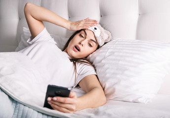 Shocked woman looking at the alarm clock on the smartphone and realizing that she overslept