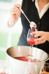 Barman pouring red cocktail- cup on the stem.
