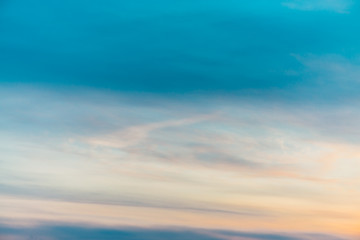 Obraz premium Sunset sky with orange yellow light clouds. Colorful smooth blue sky gradient. Natural background of sunrise. Amazing heaven at morning. Slightly cloudy evening atmosphere. Wonderful weather on dawn.