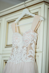 wedding dress on hanger on a wall. Beautiful gown