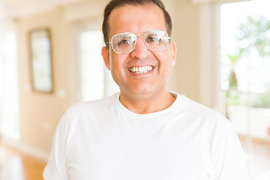 Middle age man wearing glasses smiling to the camera at home