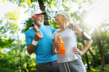 Happy fit senior couple exercising in park