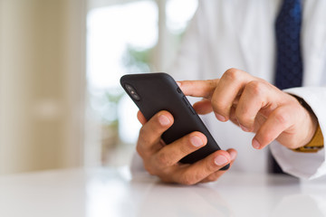 Close up middle age doctor man hands using smartphone