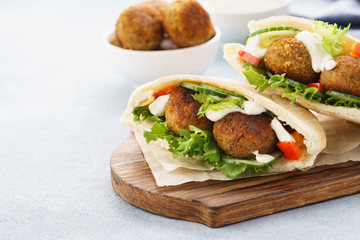 Pita breads with falafel, fresh vegetables and sauce.