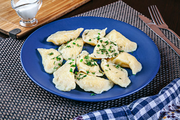 Close up view on plate with tasty homemade vareniki with parsley. Ukranian vareniki with potato and sour served on table with copy space. Useful pitcture for design or menu. Food flat lay