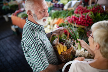 Happy senior couple with basket at the local market