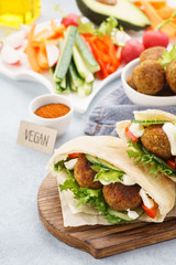Pita breads with falafel, fresh vegetable sticks and sauce.