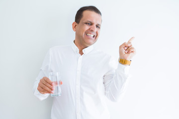 Middle age man drinking a glass of water over white background very happy pointing with hand and finger to the side