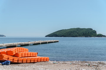 Long concrete pier in the sea. Mountain island in the background.