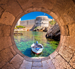 Dubrovnik small harbor under city walls view through stone carved window