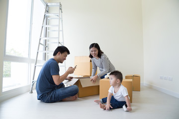 Family unpacking boxes in new home on moving day, Happy father mother and son is having fun with cardboard boxes in the bedroom of new house