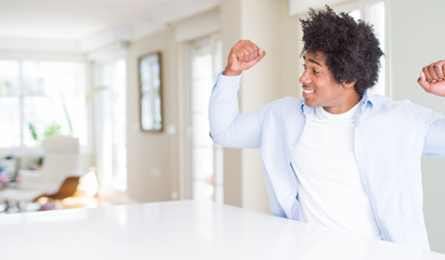 African American man at home showing arms muscles smiling proud. Fitness concept.