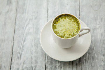 cup of hot matcha green tea latte on grey wooden background