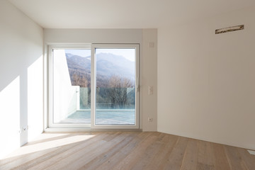 Empty room with white walls and windows overlooking the mountains