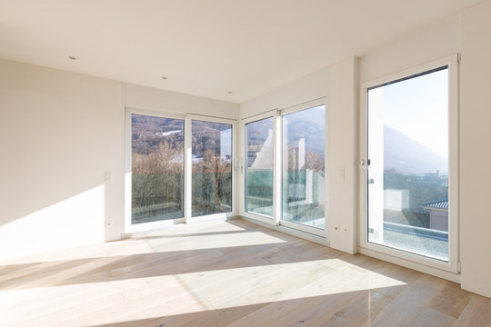 Empty room with white walls and windows overlooking the mountains