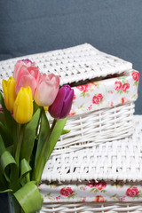 Bouquet of tulips of different colors on a gray background. Near wicker boxes.