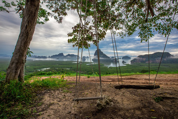 The panoramic background of the surrounding scenery (mountains, sea, islands, clouds, sky) and a wooden chair to sit and enjoy the view, is the beauty of nature during travel.