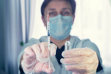 a woman in a white coat with a syringe in hand