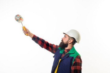 Painter. Repair tools. Bearded painter with paint roller. Painter with painting roller. Room painting job. Hard hat. Man worker. Construction. Industrial concept. Repair.