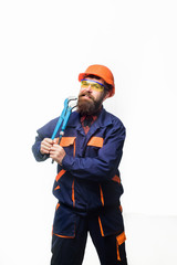 Bearded man with repair tools in hand. Repair service. Worker in helmet with pipe wrench. Bearded man in construction helmet. Uniform. Mechanic. Plumbing and renovation. Pipe wrench.