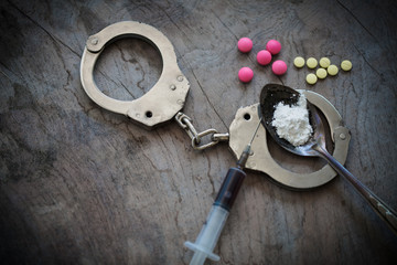 Drug syringe and cooked heroin on spoon and handcuffs . Concept - punishment for possession of...