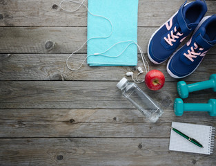 Fitness concept with sneakers dumbbells bottle of water apple