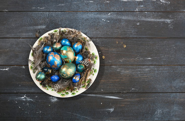 Painted colored Easter eggs on animal skin in plate on dark wooden background. Boho stile.