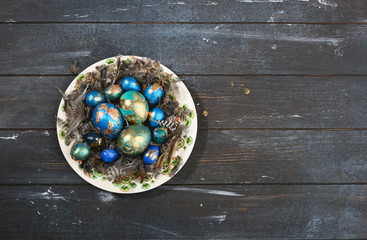 Obraz na płótnie Canvas Painted colored Easter eggs on animal skin in plate on dark wooden background. Boho stile.