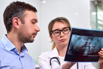 Caucasian female dentist explaining to male patient the x-ray