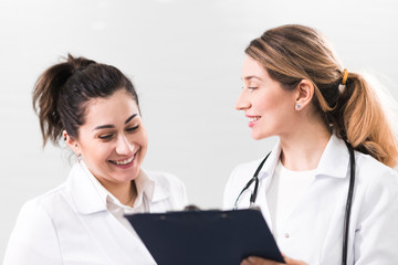Two female assistants dressed in white coats talking to each other in the dentistry center