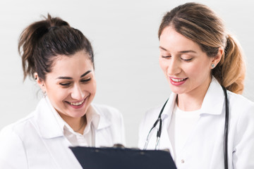 Two female assistants dressed in white coats talking to each other in the dentistry center