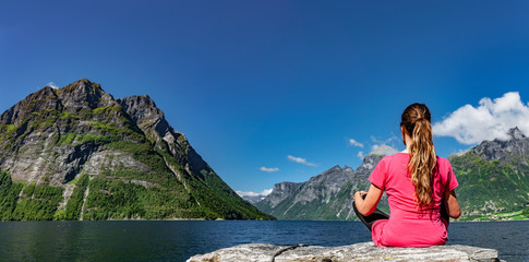 Naklejka na ściany i meble Frau sitzt an einem Fjord