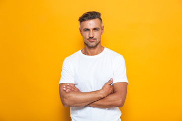 Handsome serious man posing isolated over yellow wall background.