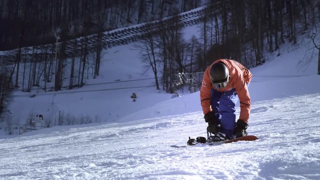 Professional rider puts snowboard on his feet. Button fasteners. Getting ready to ski or snowboard. Enjoys winter sports