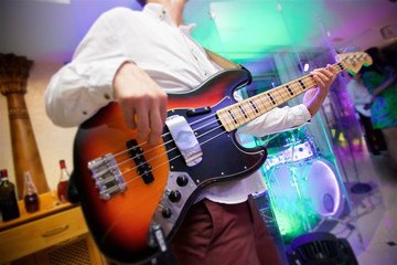 Obraz premium Stringed musical instrument electric bass guitar in the hands of a male musician.