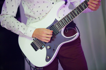 Stringed musical instrument electric guitar in the hands of a male musician.
