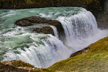 View of a waterfall in Iceland. Water flows from top to bottom.