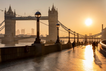 Sonnenaufgang über der Tower Bridge in London mit Silhouetten von Personen die zur Arbeit gehen