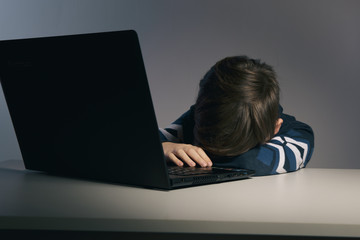 Closeup picture of bullying teen boy feeling upset infront of computer. Stressed sad boy is...