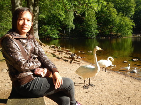 Happy wonam enjoying outdoors by the lake with sawns in the background