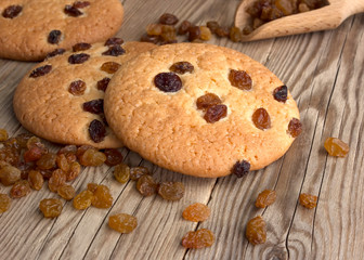 Oatmeal cookies with raisins,  on a dark wooden background with a wooden spoon