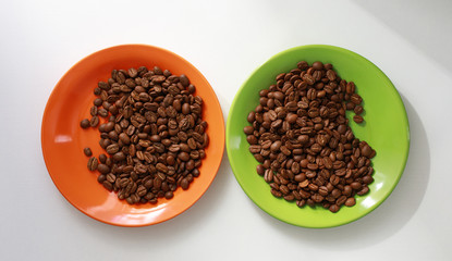 Orange and green saucer with coffee beans on white table