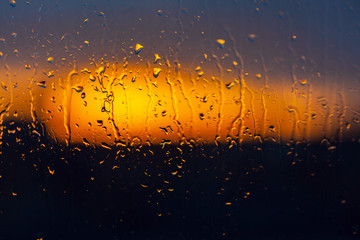 Blurred sunset background behind wet window