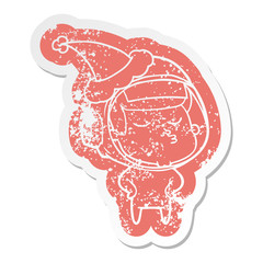 cartoon distressed sticker of a confident astronaut wearing santa hat