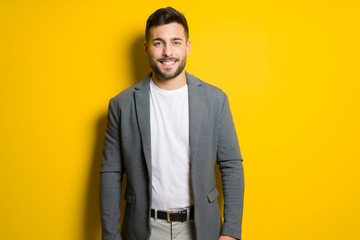 Fototapeta premium Young handsome man possing and modeling over yellow isolated background