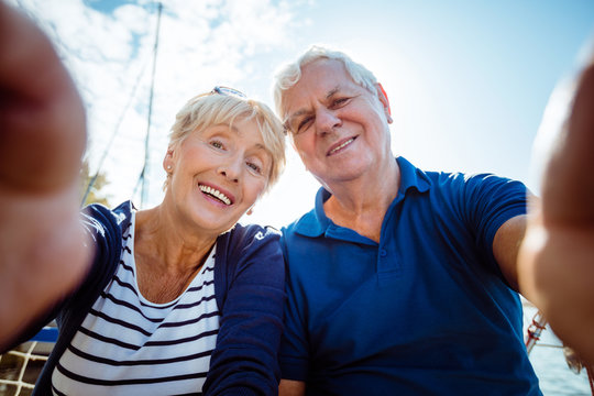 Smiling senior couple taking selfie on sailboat
