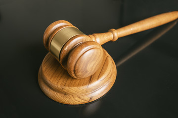 judge or auction Gavel on a wood block in courtroom, dark background