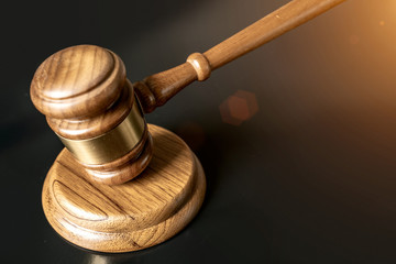 judge or auction Gavel on a wood block in courtroom, dark background