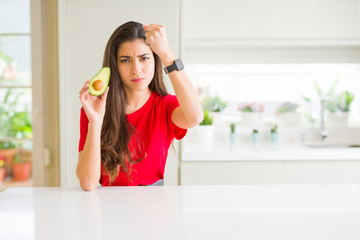 Fototapeta na wymiar Young woman eating healthy avocado annoyed and frustrated shouting with anger, crazy and yelling with raised hand, anger concept